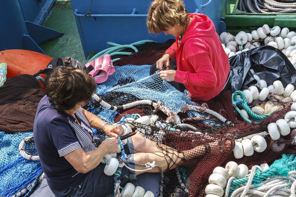 Grupo de mujeres reparando redes en el puerto de Getaria. © Javier Mina Rodríguez.